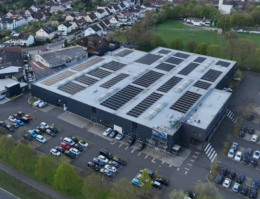 Luftaufnahme des Produktionsstandorts in Fulda mit Dach-PV-Anlage inmitten der umliegenden Wohnbebauung.