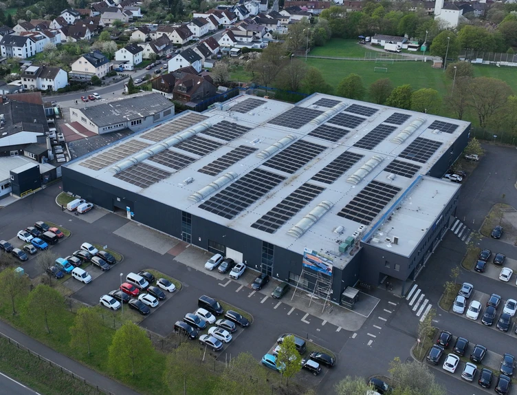 Luftaufnahme des Produktionsstandorts in Fulda mit Dach-PV-Anlage inmitten der umliegenden Wohnbebauung.
